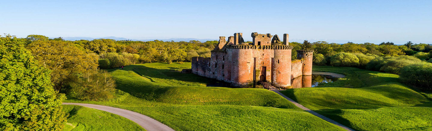 Encircled by a moat Caerlaverock Castle sits in a clearing surrounded by trees 
